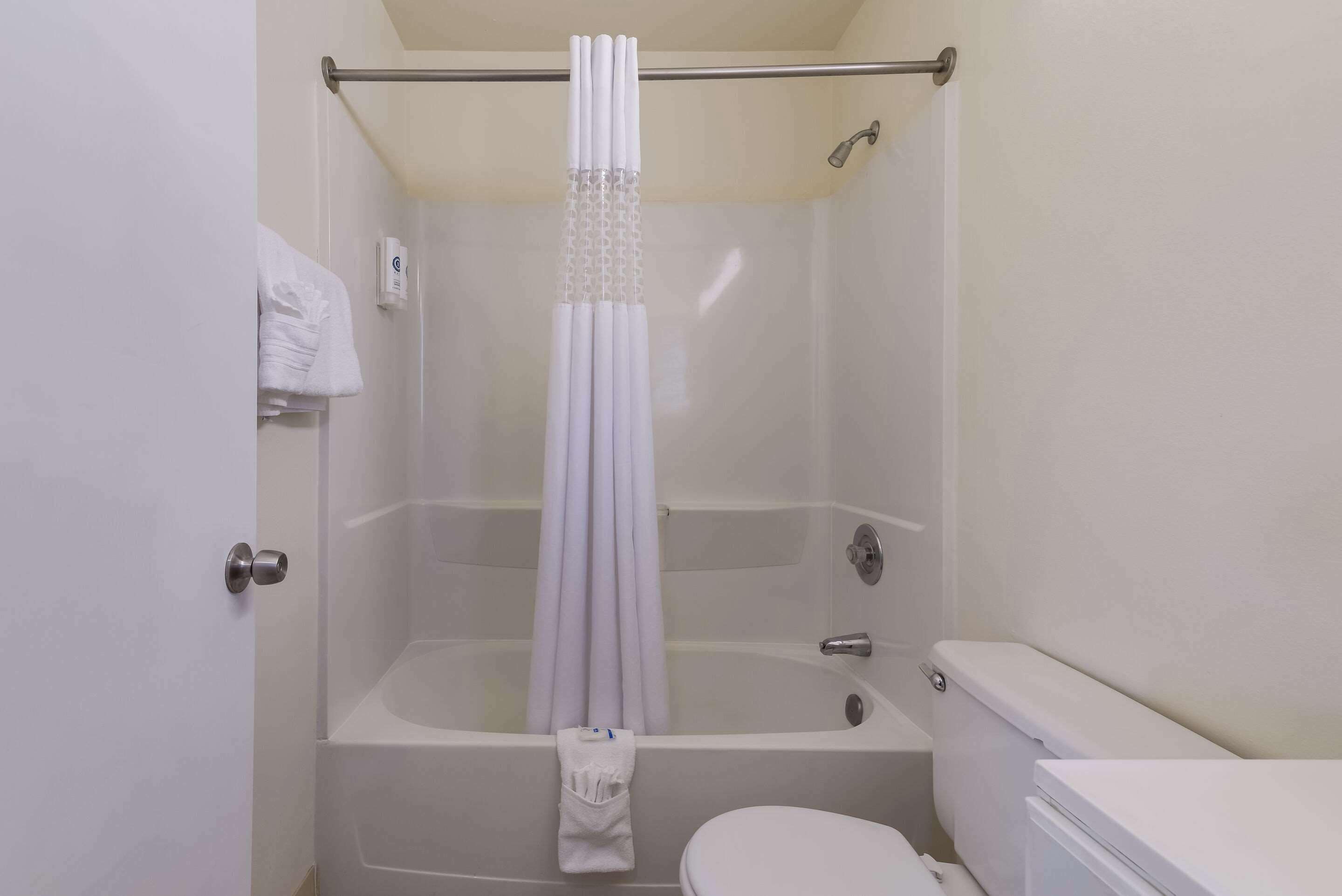A bathroom with a bathtub, toilet, and a shower curtain.