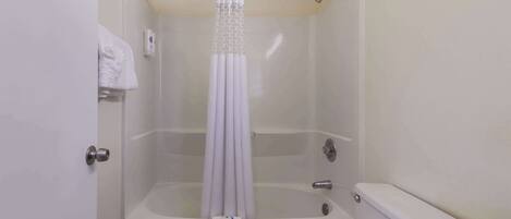 A bathroom with a bathtub, toilet, and a shower curtain.