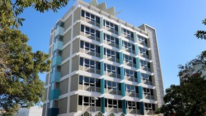 Un edificio de varias plantas con un diseño arquitectónico moderno, que cuenta con una serie de balcones y ventanas amplias.