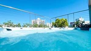 Piscina en la azotea con agua azul cristalina, rodeada por barandilla de metal y vegetación.