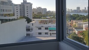 Una habitación con un amplio ventanal que da a un paisaje urbano, con edificios modernos y un cielo despejado.