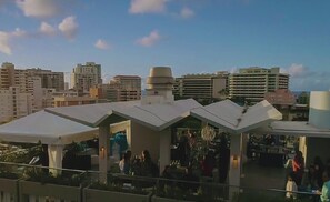 A rooftop bar with multiple white umbrellas, a bar area, and a view of the city skyline.