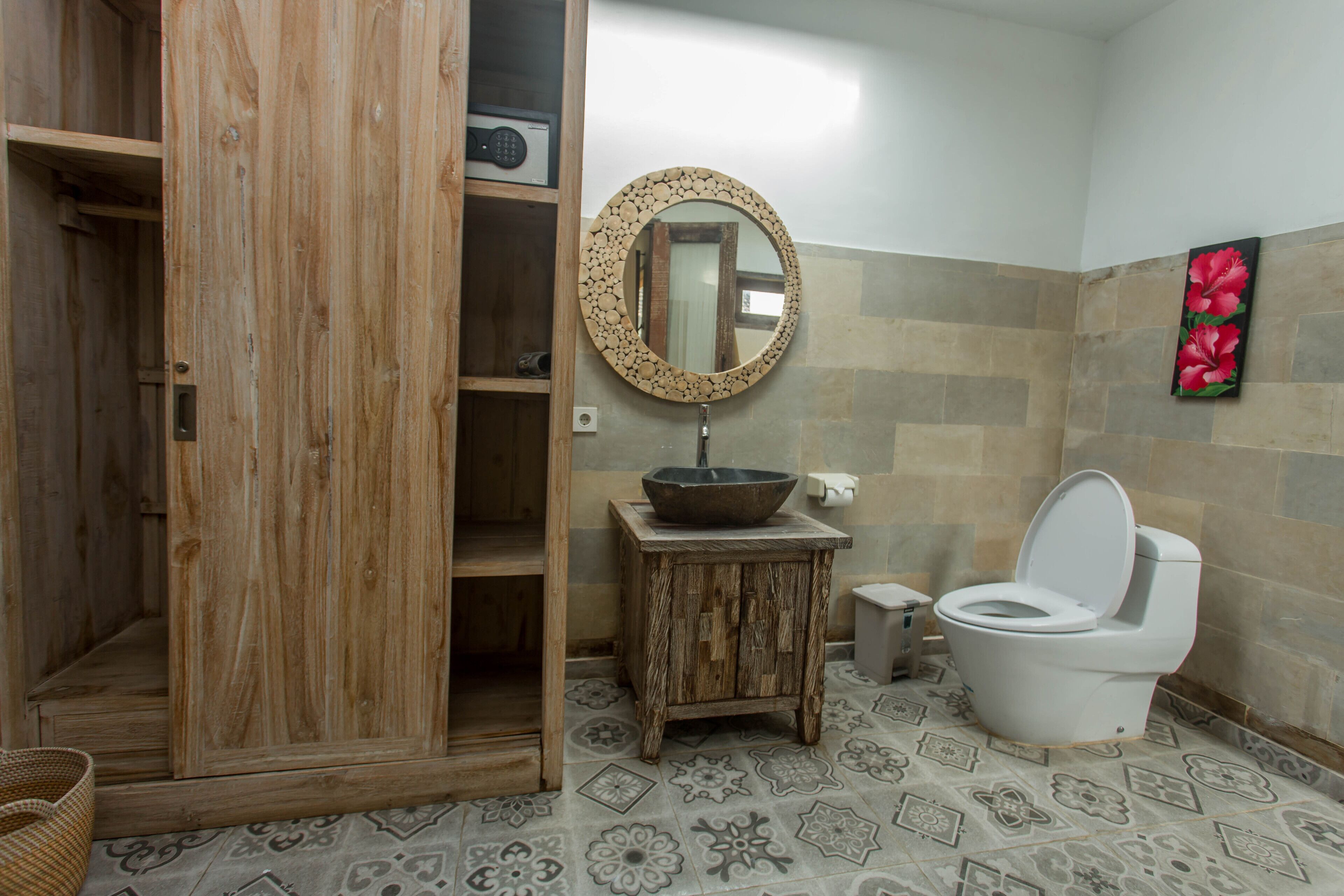 A bathroom with a wooden cabinet, a round mirror, a sink, and a toilet.