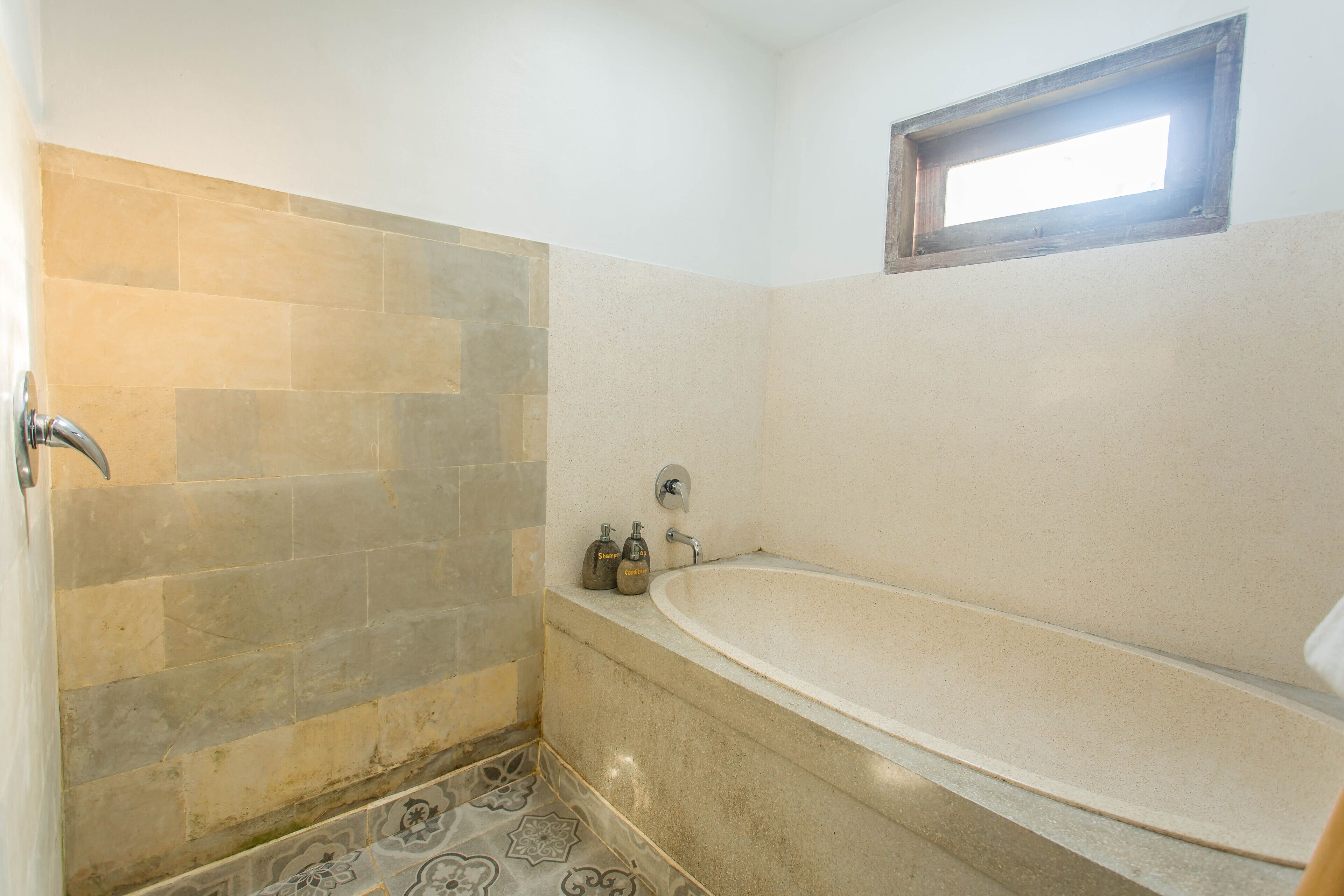 Un baño con bañera, zona de ducha y ventana.