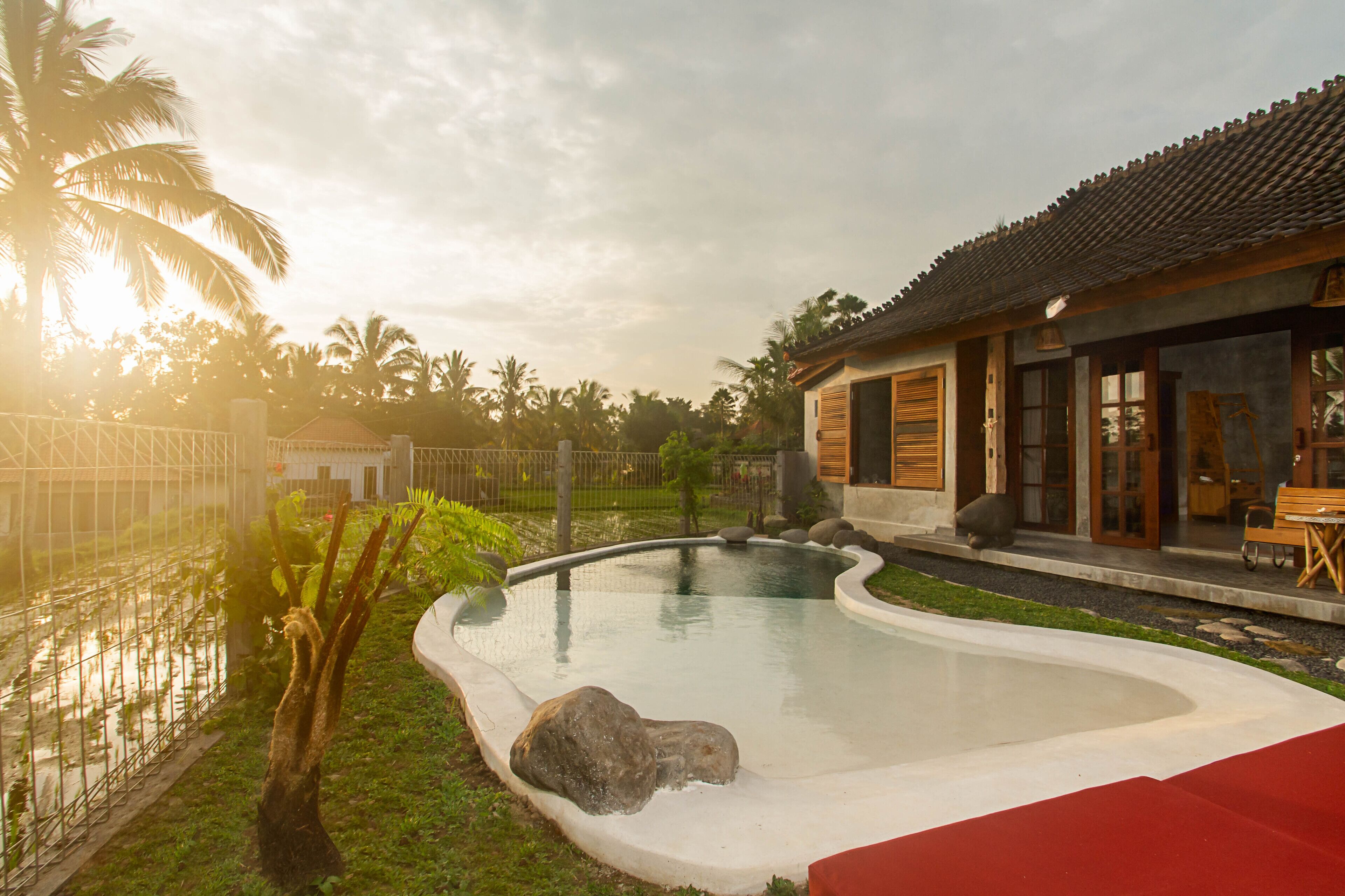 A swimming pool with a curved edge, a wooden deck, and a building with a tiled roof.