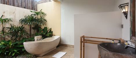 Ein Badezimmer mit freistehender Badewanne, einer Holzbadewanne und einem Waschbecken mit Vessel-Becken.