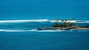 A coastal view with a small island featuring palm trees and a clear blue ocean. - Villa Karingal (Senggigi)