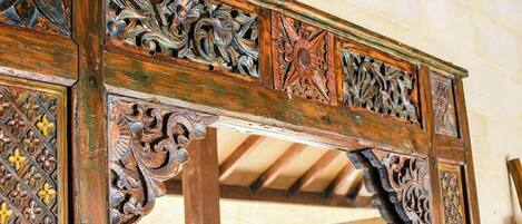 A detailed wooden structure with intricate carvings and a stone wall in the background.