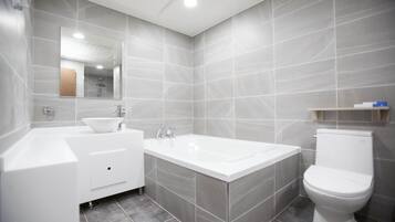 Een moderne badkamer met een bad, toilet en wastafel.