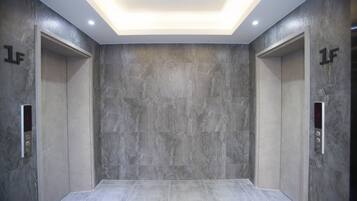 A modern elevator with grey marble walls and a digital control panel.