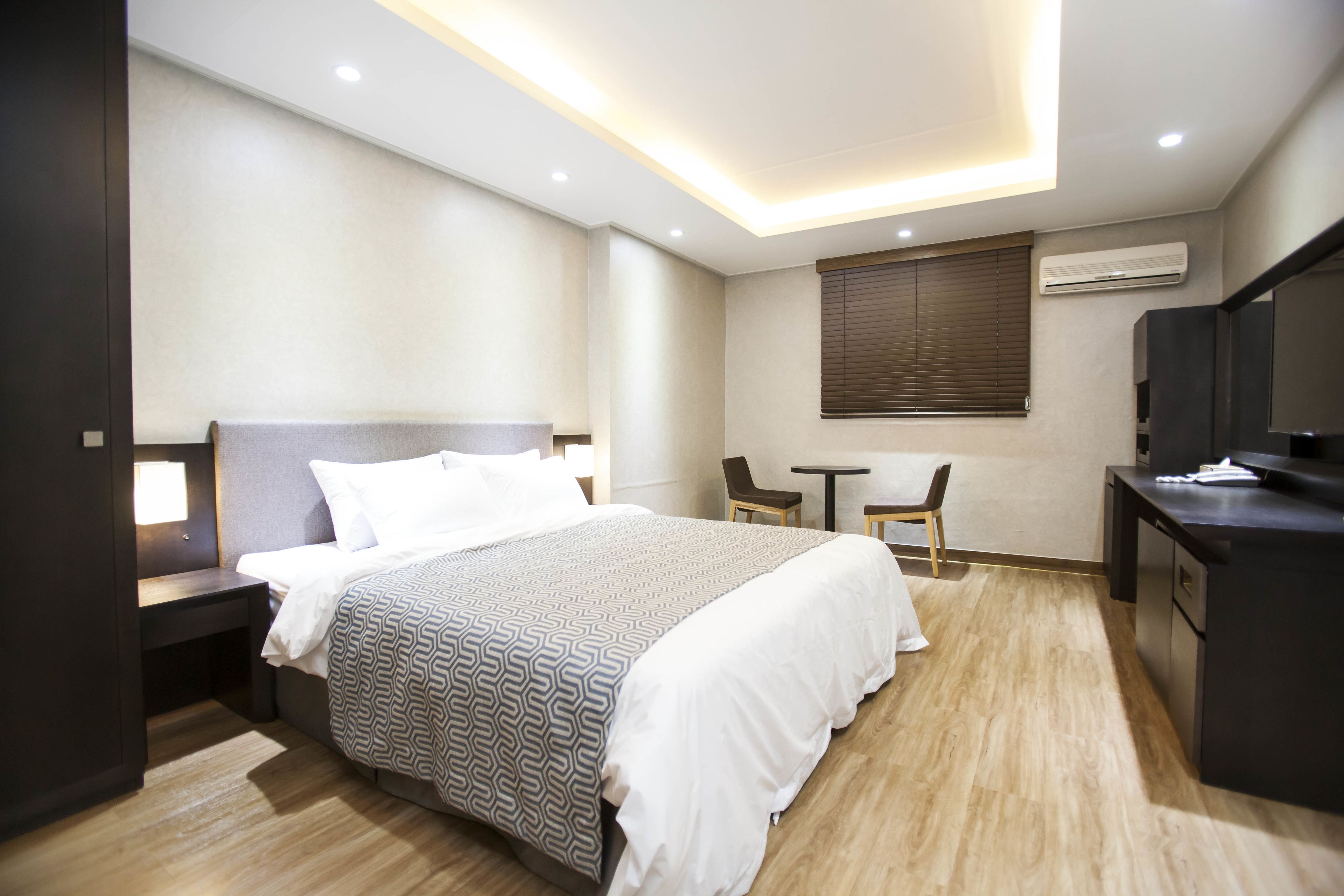 A modern hotel room with a large bed, bedside tables, a desk, and a television.