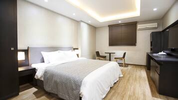 Quarto de hotel moderno com uma cama grande, mesas de cabeceira, escrivaninha e televisão.