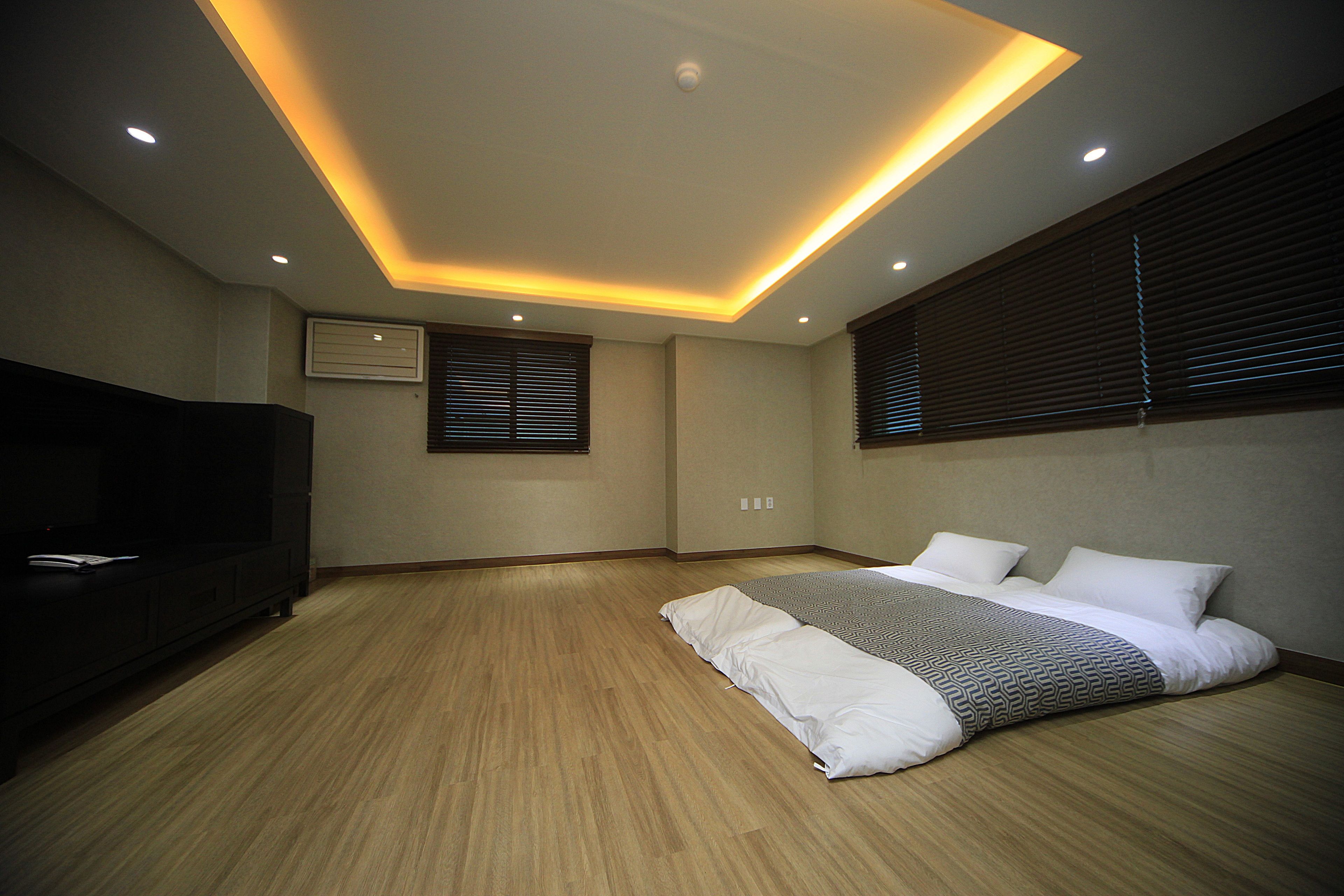 Une chambre à coucher avec un lit, un téléviseur et un luminaire fixé au plafond.