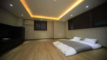 Une chambre à coucher avec un lit, un téléviseur et un luminaire fixé au plafond.