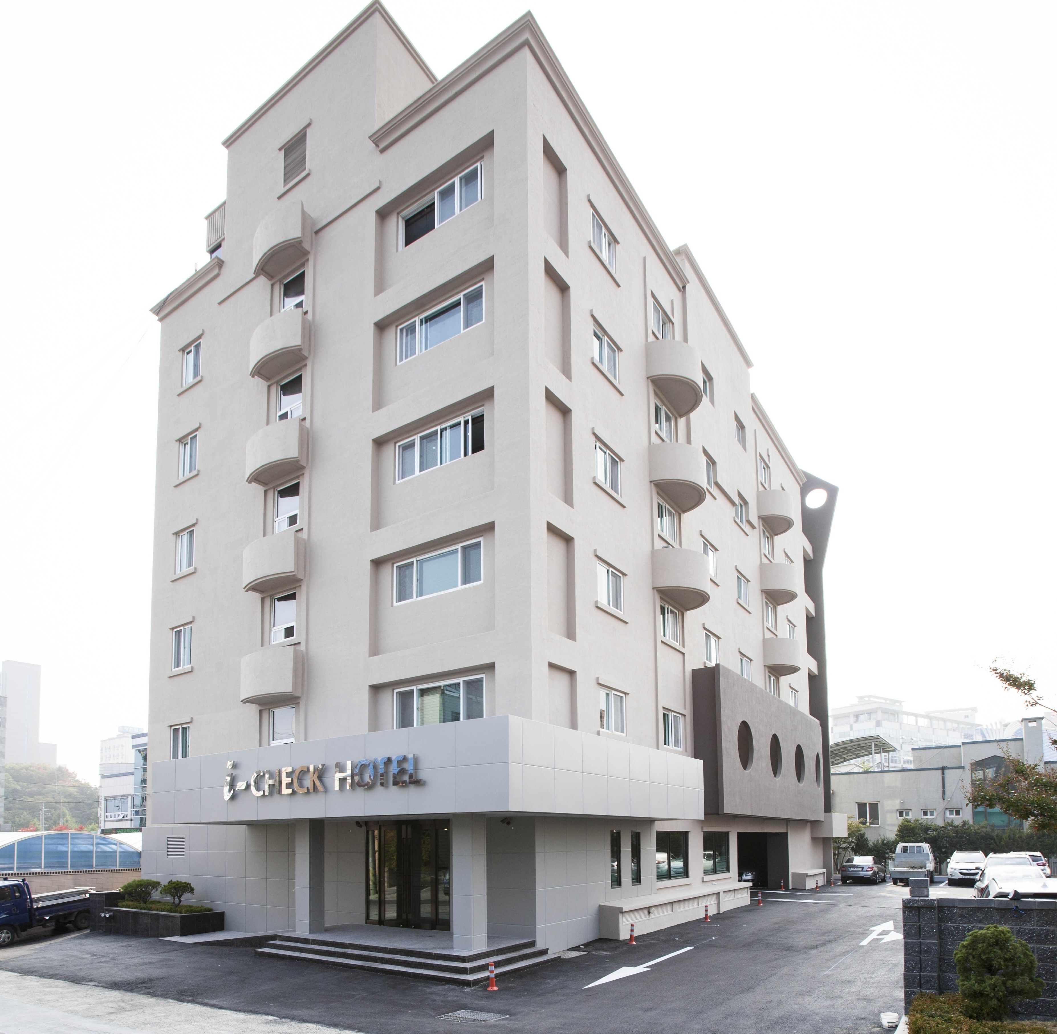 Ein modernes Hotel mit flacher Fassade, mehreren Balkonen und einem markanten Eingang.