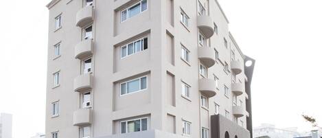 Ein modernes Hotel mit flacher Fassade, mehreren Balkonen und einem markanten Eingang.