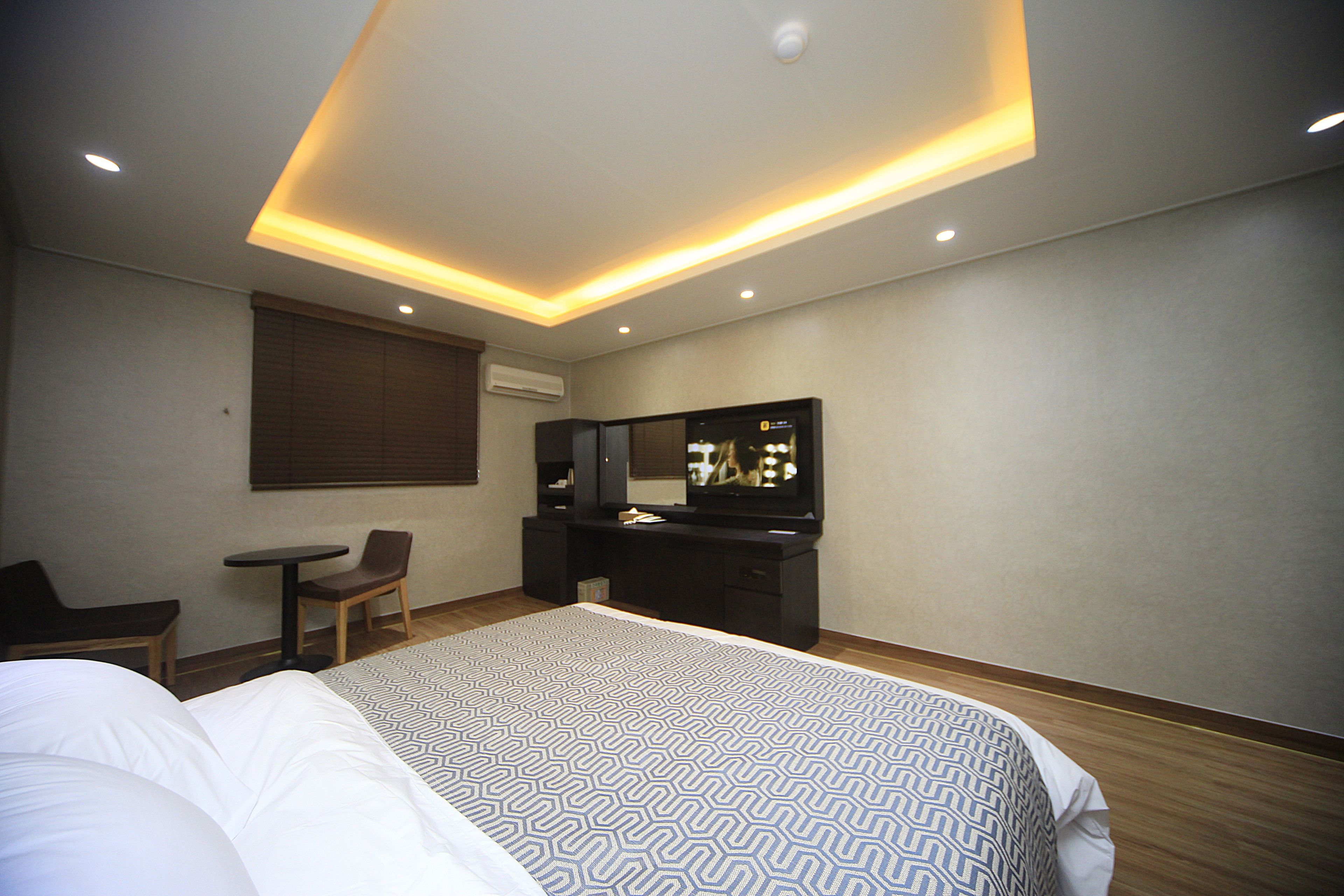 A hotel room with a bed, a desk, a chair, a television, and a mirror.