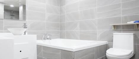 Un baño moderno con lavamanos, bañera y retrete blancos.