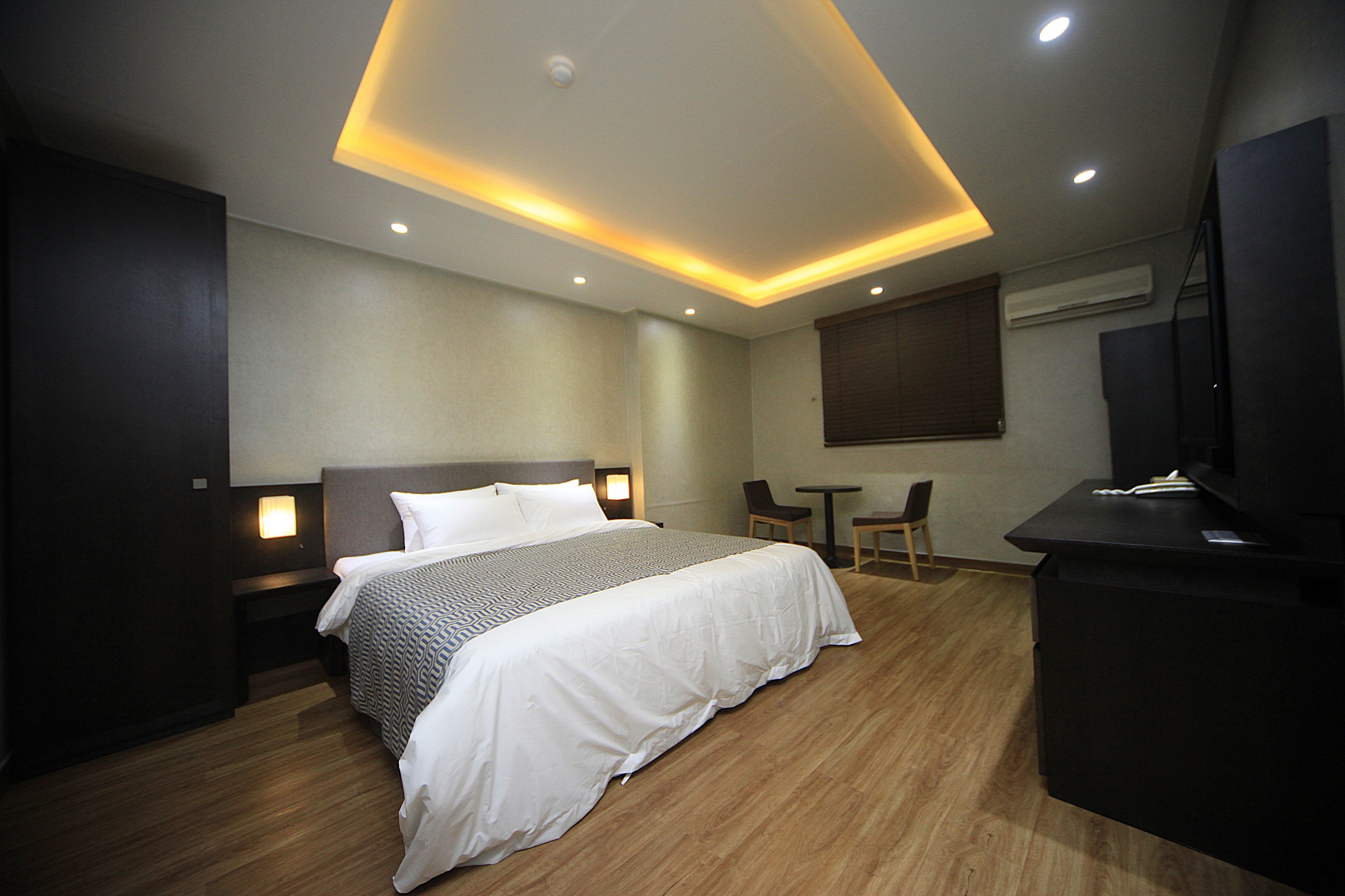 Une chambre d’hôtel moderne, dotée d’un grand lit, de tables de chevet, d’un bureau et d’une télévision.