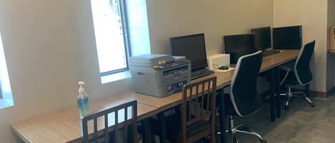 Un espacio de trabajo con escritorio, sillas, computadoras e impresora.