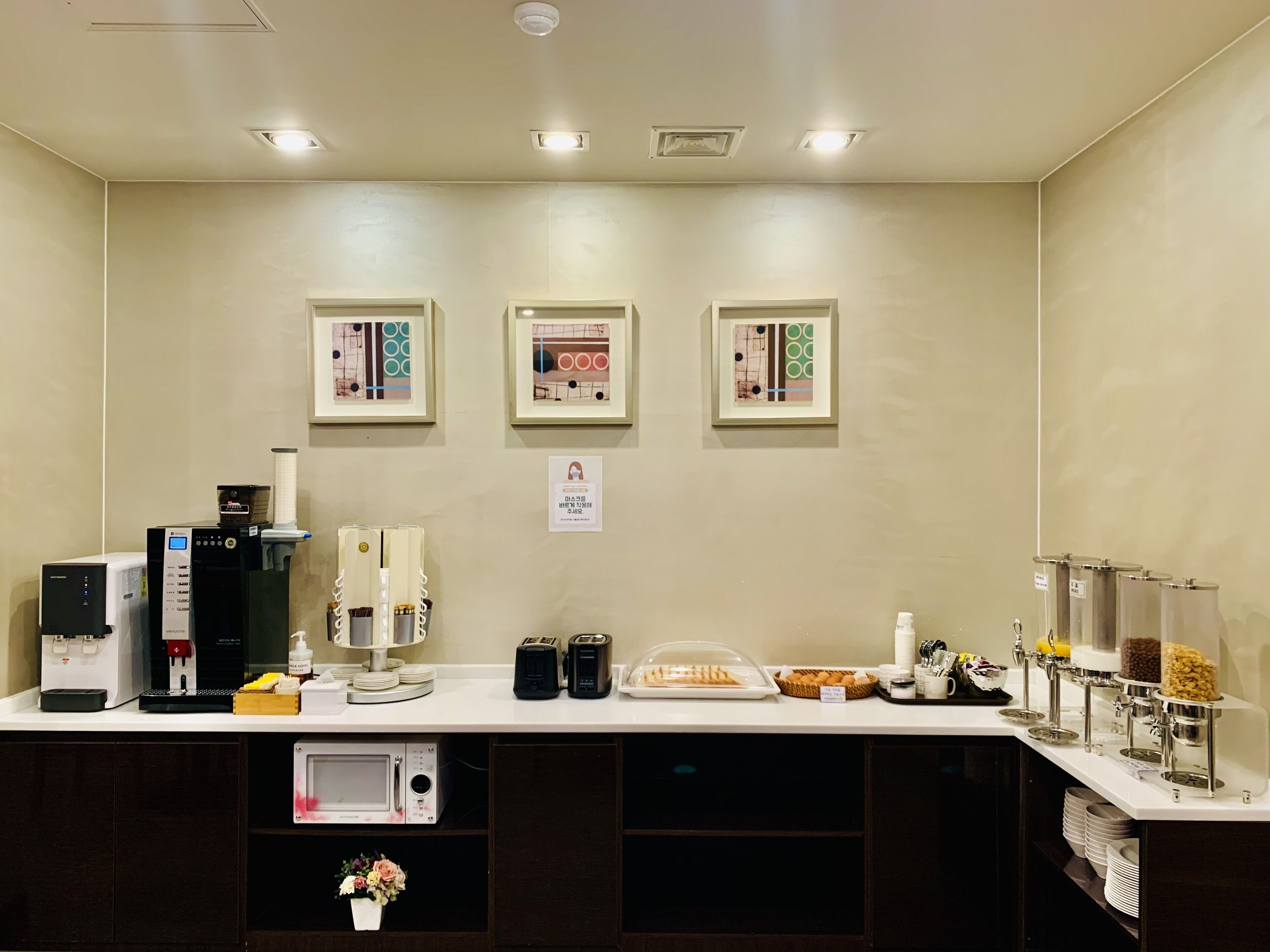Una barra de desayuno con máquinas de café, un microondas y una variedad de alimentos.