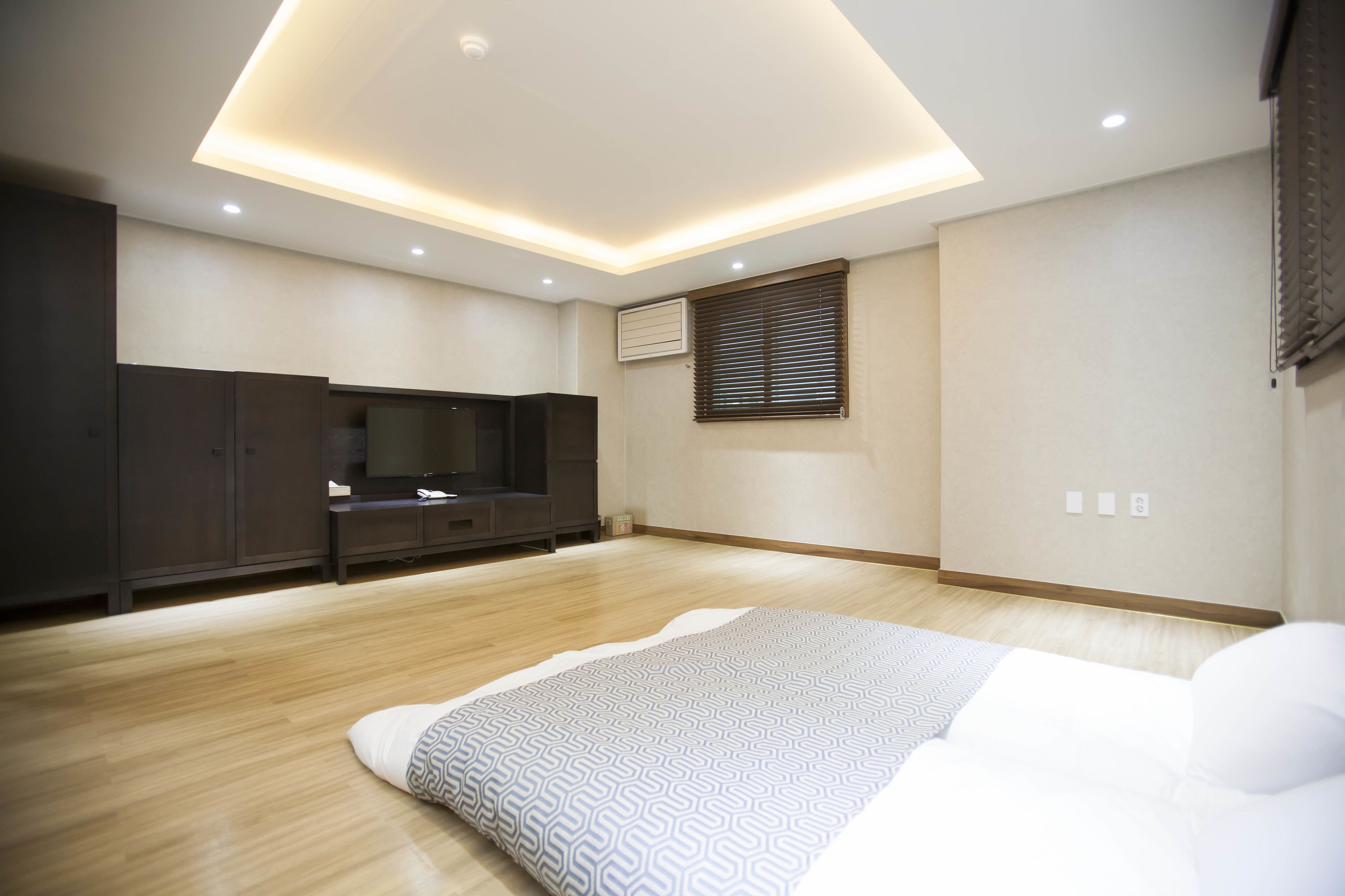 A modern bedroom with a large bed, a TV, and built-in cabinets.