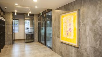 En modern hotellobby med ett marmorgolv, glasdörrar och ett inramat konstverk på väggen.