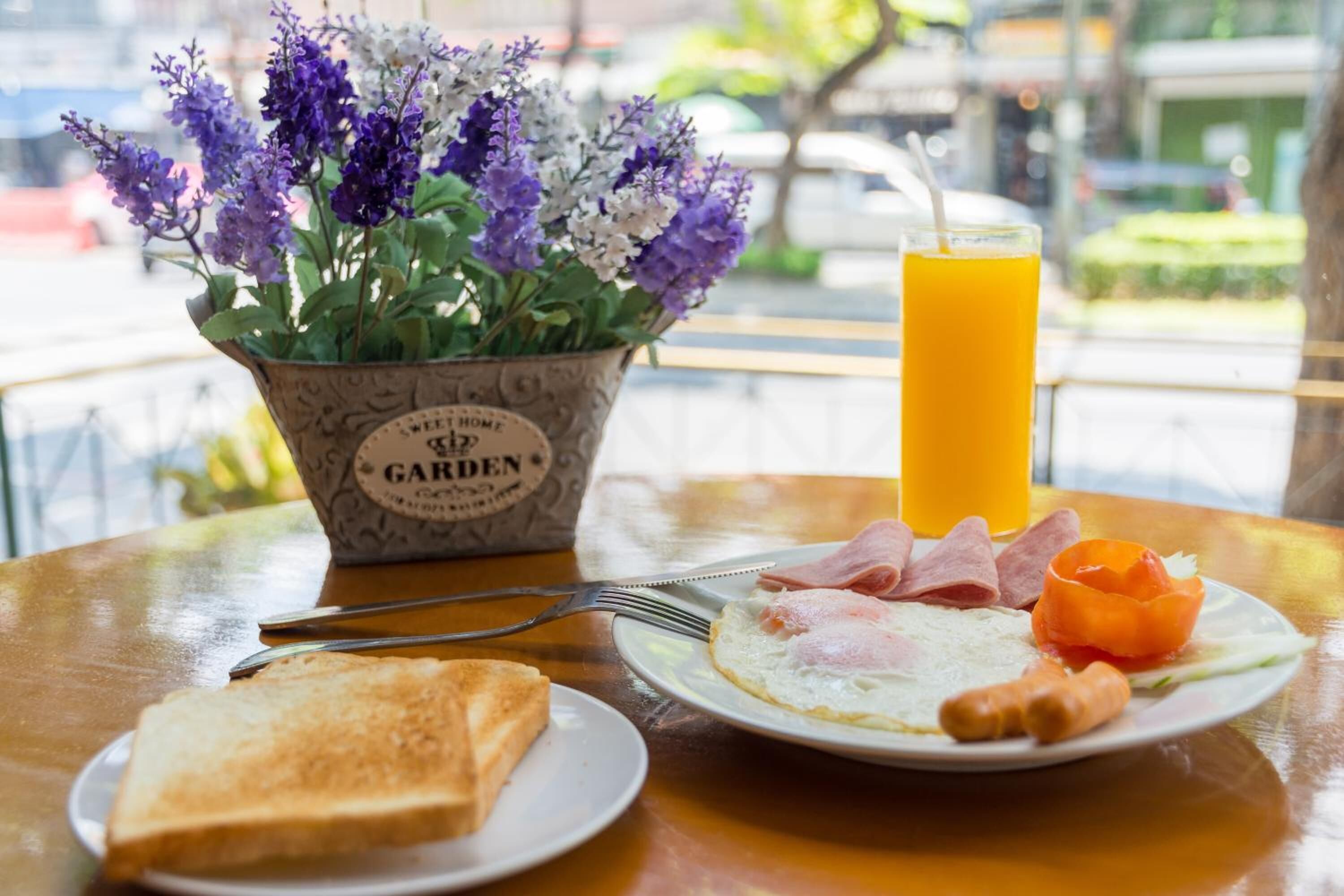 A breakfast setting with a plate of eggs, ham, and toast, a glass of orange juice, and a flower pot labeled "GARDEN".