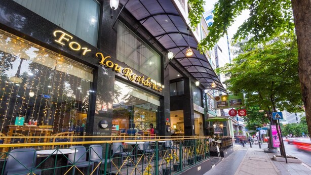 A restaurant with outdoor seating, a glass facade, and a sign reading "For You Residence". - For You Residence (Bangkok)