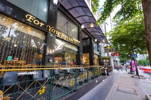 A restaurant with outdoor seating, a glass facade, and a sign reading "For You Residence". - For You Residence (Bangkok)
