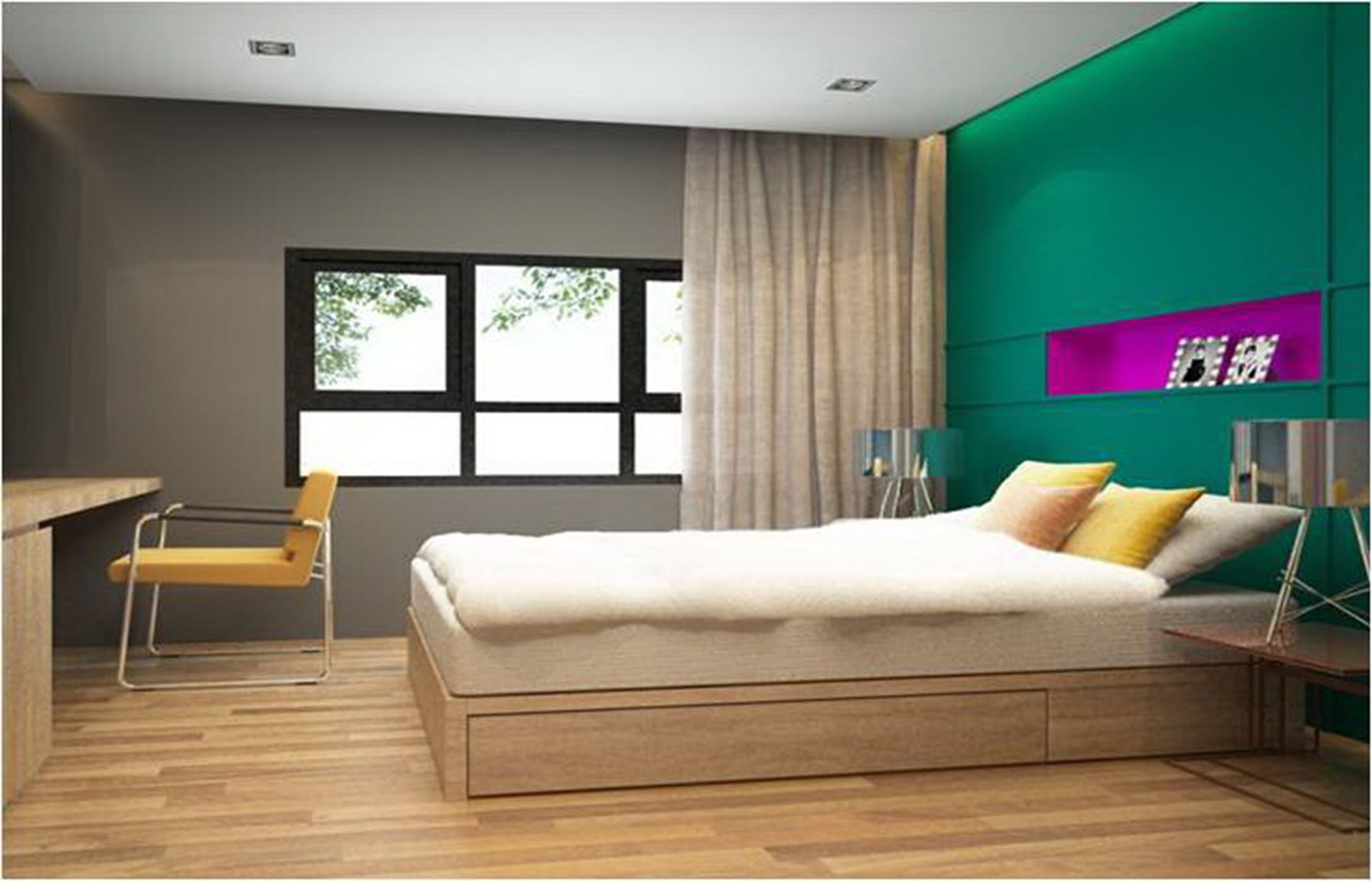 A modern bedroom with a large bed, a desk, and a chair. There is a window with curtains, a green accent wall, and a shelf with decorative items.
