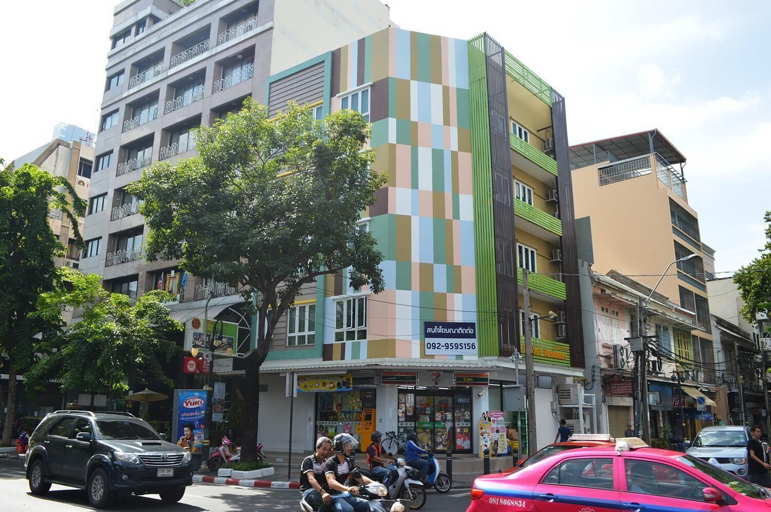A multi-story building with a colorful facade, a visible storefront, and a tree in front.
