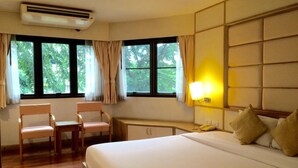 A hotel room with a bed, two chairs, a desk, and a window with curtains. - For You Residence (Bangkok)