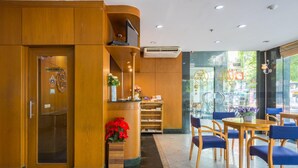 A hotel lobby with a reception desk, seating area, and a glass door leading outside. - For You Residence (Bangkok)