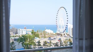 A view of a coastal area with a large Ferris wheel, buildings, and a parking lot. - Sokcho Good Morning Hotel and Resort (Sokcho)