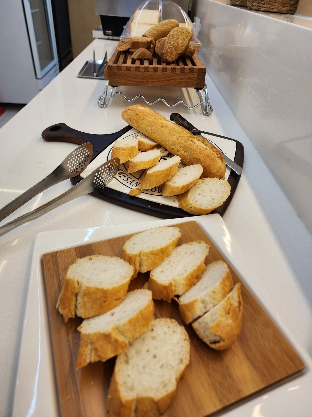 A kitchen counter with a loaf of bread, a grater, and a cutting board with sliced bread.