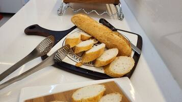 A kitchen counter with a loaf of bread, a grater, and a cutting board with sliced bread.