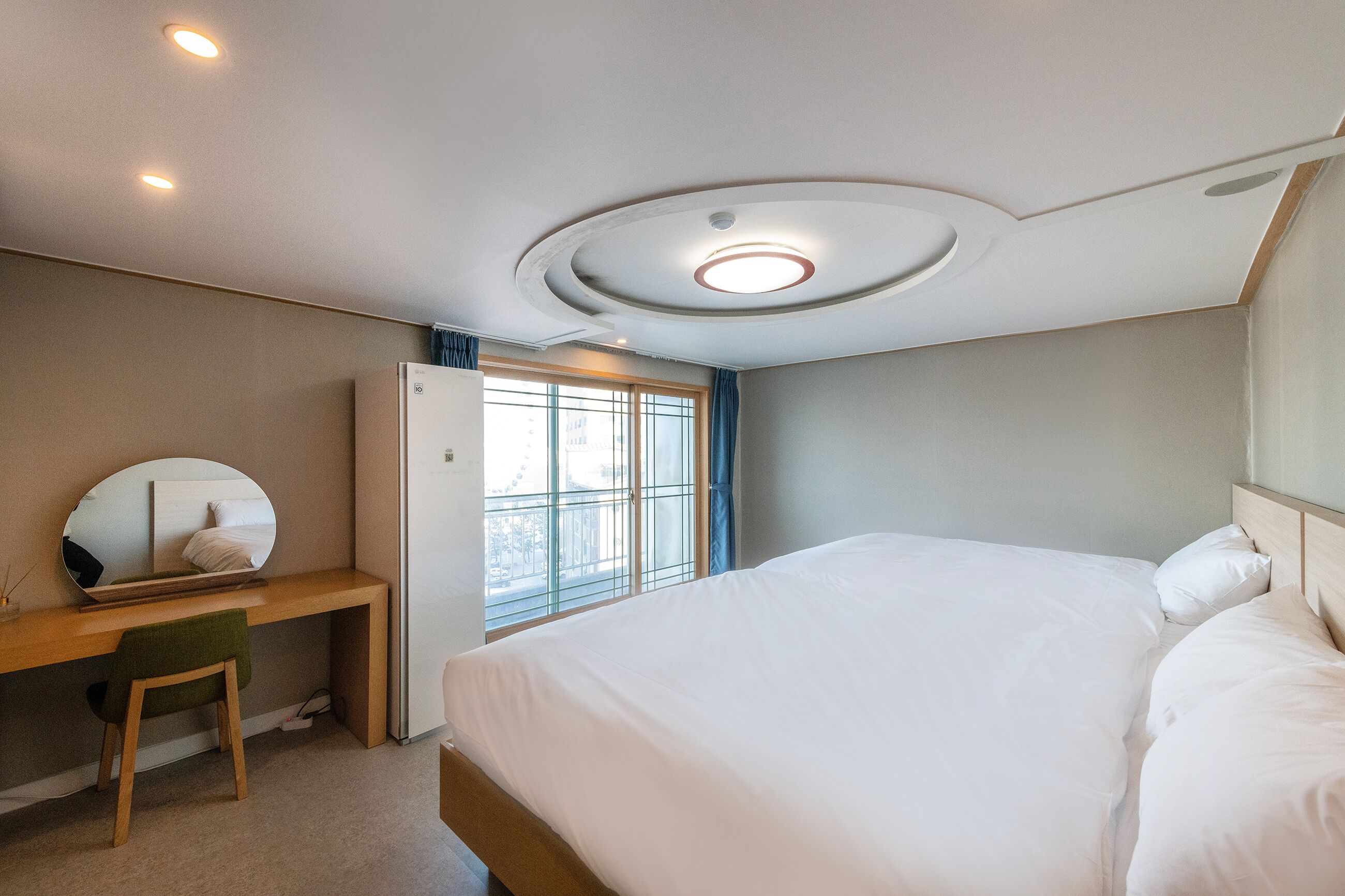 A bedroom with a bed, a desk, and a window.