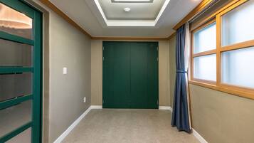 A hallway with a green door, a window with a curtain, and a ceiling light.