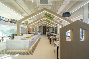Una cafetería moderna con mostradores de mármol, vigas de madera y vistas de la ciudad a través de amplios ventanales.