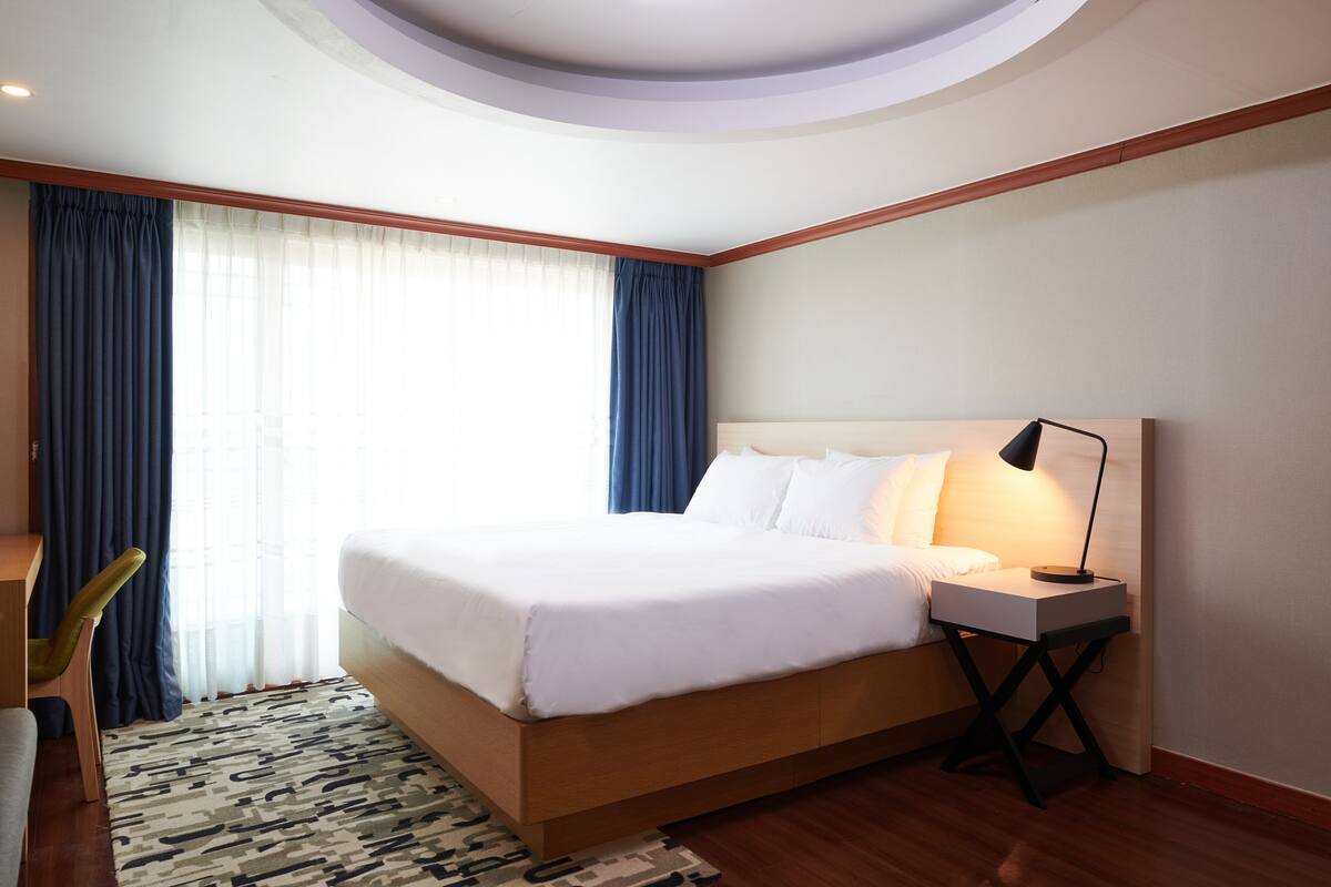 A hotel room with a wooden bed, a desk, and a chair.