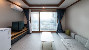 A modern living room with a flat-screen TV on a wooden stand, a white table, and a grey sofa. - Sokcho Good Morning Hotel and Resort (Sokcho)