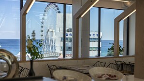 A dining area with a view of a Ferris wheel and the sea. - Sokcho Good Morning Hotel and Resort (Sokcho)