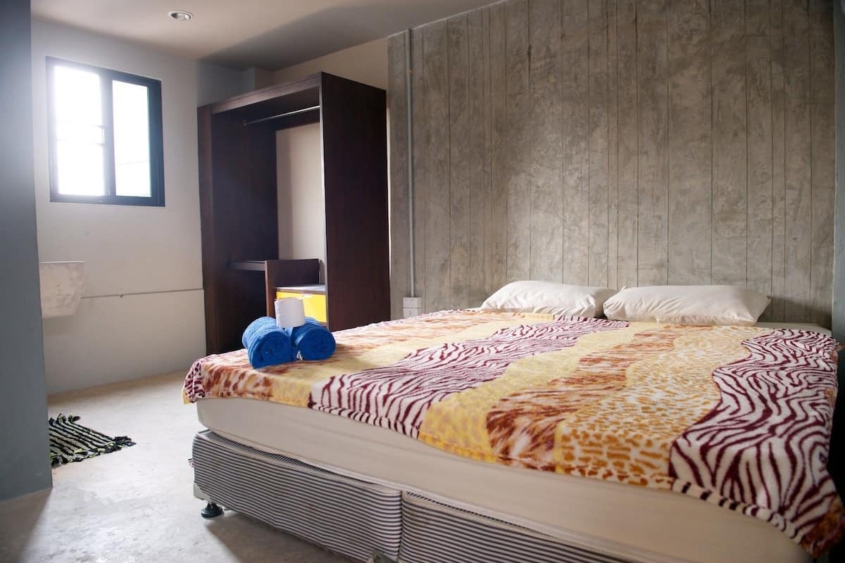 A bedroom with a bed, a wardrobe, and a window.
