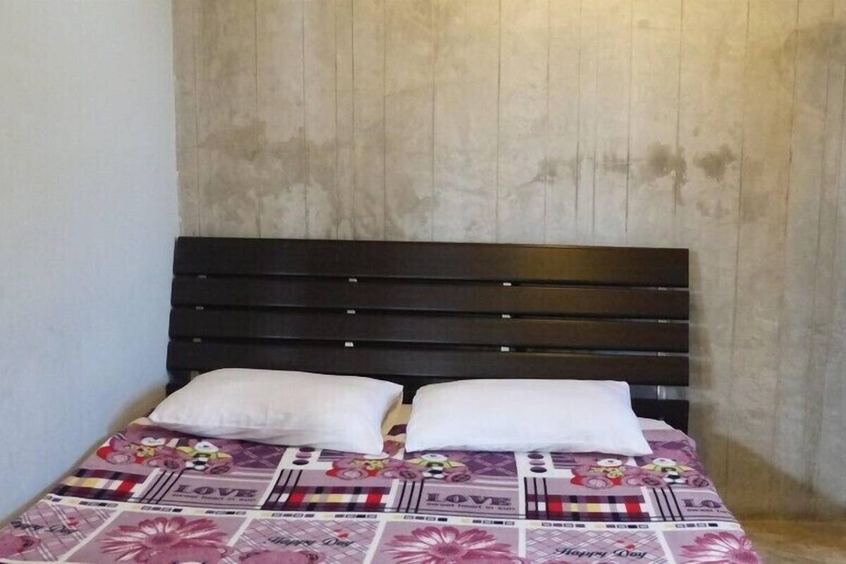 A bed with a dark headboard and a floral-patterned bedspread.
