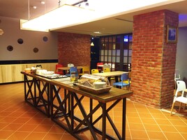 Un restaurante con una larga mesa de madera, paredes de ladrillo rojo y sillas coloridas.