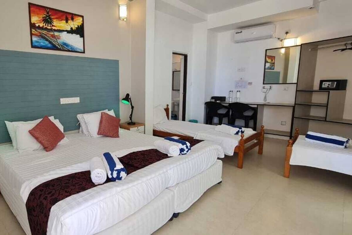 A hotel room with two beds, a desk, a chair, a mirror, and a painting on the wall.