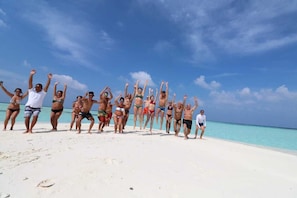 A group of people on a beach with clear skies and turquoise water. - Liberty Guest House Maldives (Mahibadhoo)