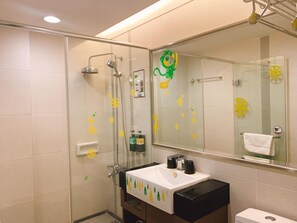 A modern bathroom with a glass shower enclosure, a sink with decorative soap dispensers, and a toilet.