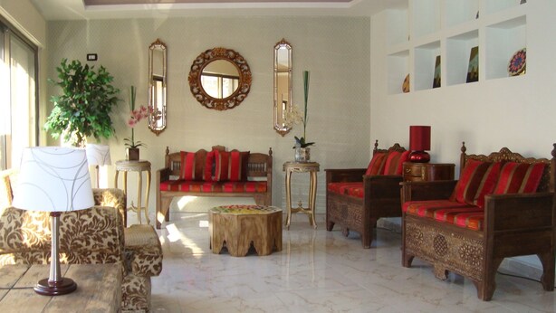 A spacious living room with a sofa, armchairs, a coffee table, and a lamp. - Rafi Hotel Amman (Amman)